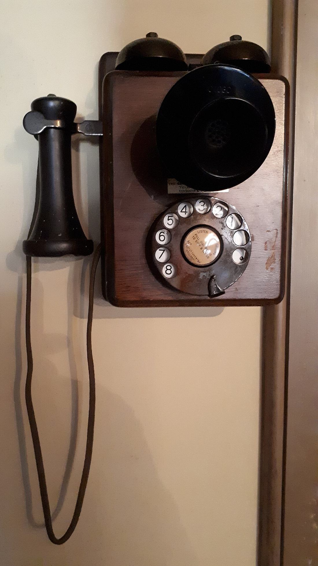 An old wooden rotary telephone on a wall
